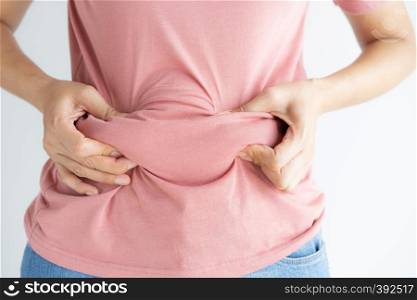 Woman hand holding her own belly fat and cellulite on white background. Women before weight loss and shape up healthy stomach muscle concept.