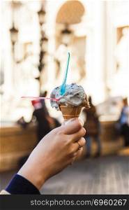 Woman hand holding ice cream.. Woman hand holding ice cream in cone. At Trevi fountain.