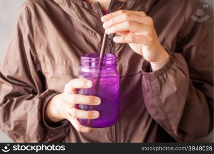Woman hand holding iced drink in violet glass with vintage filter, stock photo