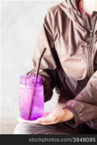 Woman hand holding iced drink in violet glass with vintage filter, stock photo