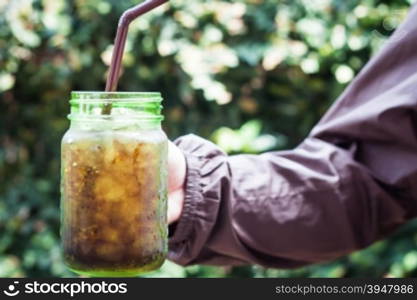 Woman hand holding iced soda in green glass, stock photo
