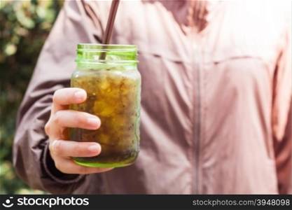 Woman hand holding iced soda in green glass with vintage filter, stock photo