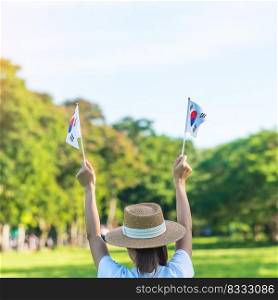 Woman hand holding Korea flag on nature background. National Foundation, Gaecheonjeol, public Nation holiday, National Liberation Day of Korea and happy celebration concepts