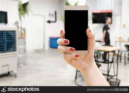 Woman hand holding mobile smart-phones screen for mockup design and others app display background, Has a blurred restaurant background