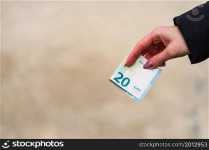 Woman hand holding or giving money like a bribe or tips. World money concept, close up of 20 EURO banknote, photo of EUR currency isolated. Hand holding money, EURO currency
