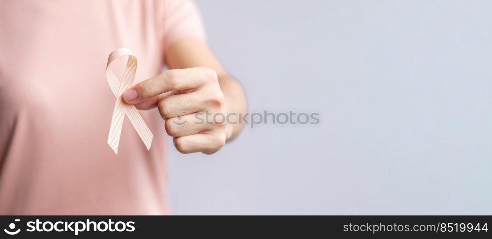 woman hand holding Peach Ribbon for September Uterine Cancer Awareness month. Healthcare and World cancer day concept