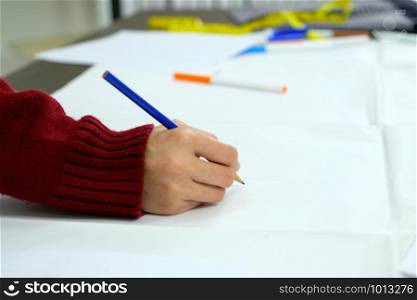 Woman hand holding pencil drawing and skectching creative design art ideas on white paper at working desk