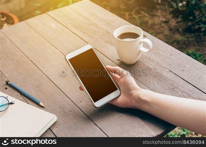 Woman hand holding phone with blank copy space screen for your advertising. Hand woman using phone in coffee shop.