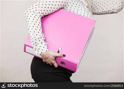 Woman hand holding pink binder with many documents. Office, bookkeeping objects concept.. Woman holding pink binder with documents