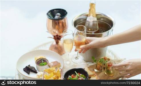 Woman hand holds glass of wine with different snacks and appetizers food at a cocktail party.