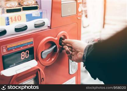 Woman hand inserting coin in vending machine at street public.