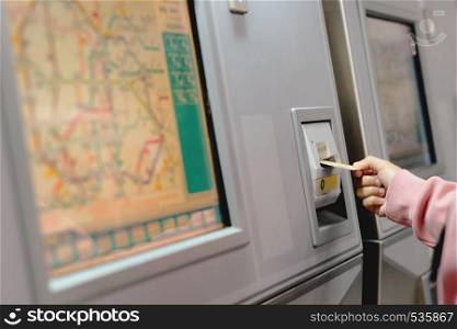 Woman hand inserts card to buy subway train ticket in machine. Transportation concept