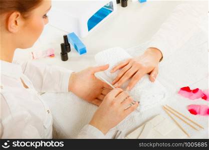 Woman hand on towel, beautician file nails. Beauty wellness spa treatment, manicure concept. Woman getting manicure done file nails