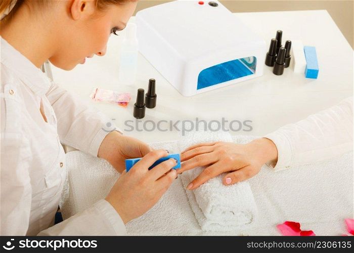 Woman hand on towel, beautician file nails. Beauty wellness spa treatment, manicure concept. Woman getting manicure done file nails
