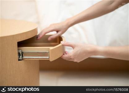 Woman hand opening a drawer in the wooden table.