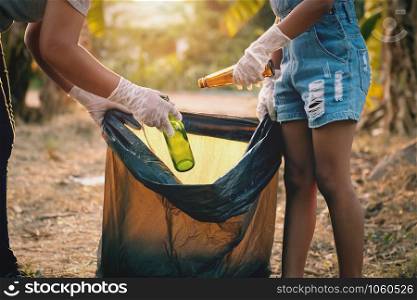 woman hand picking up garbage glass bottle for cleaning at park