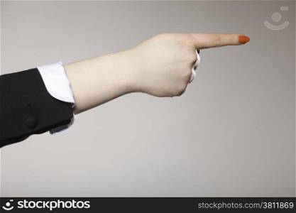 Woman hand pointing direction to follow with index finger gray background