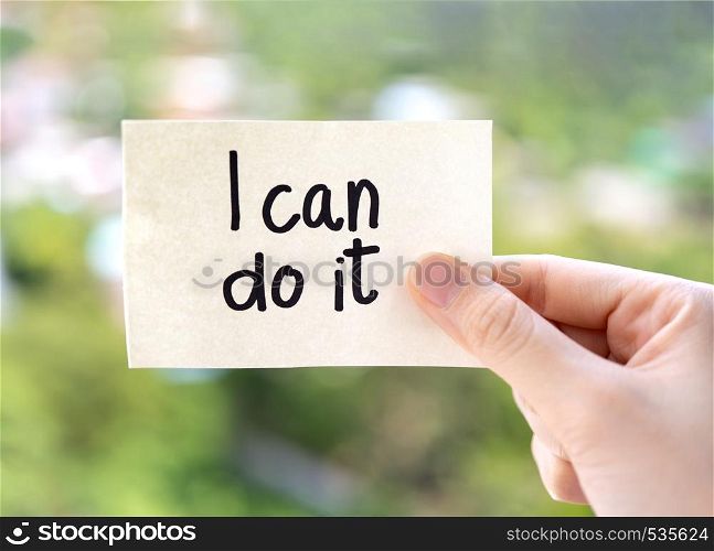 Woman hand showing I can do it texts on paper note on green nature background. Positive attitude, self belief and motivation concept.