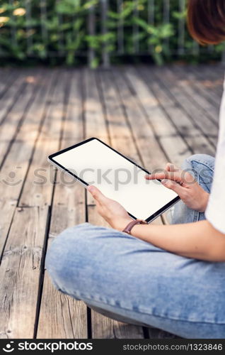 Woman hand sitting and holding digital tablet with blank screen on the park.