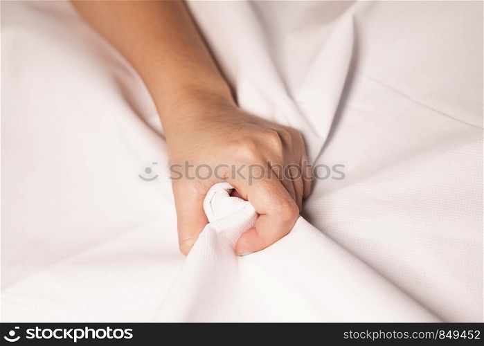 Woman hand squeezing bed sheets color white