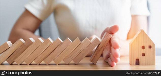 woman hand stop falling wood blocks and protect house model. Crisis, fall Business, Risk, Economic recession, Developer, Real Estate and Property concept