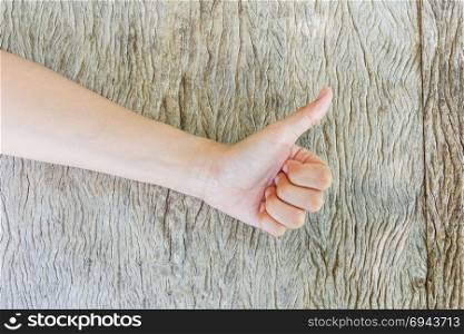 Woman hand thumbs up on wooden background.