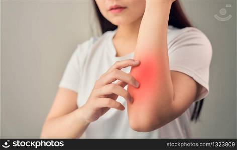 Woman hand touching elbow from chronic joint rheumatism and there is so much suffering. on the gray background.