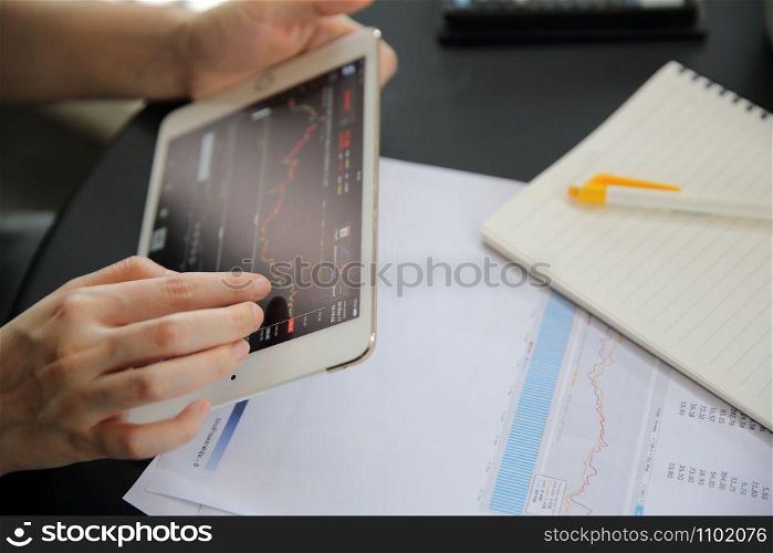 Woman hand Trading online on tablet with business paper and coffee