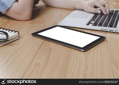 woman hand typing on computer notebook with tablet on wooden desk