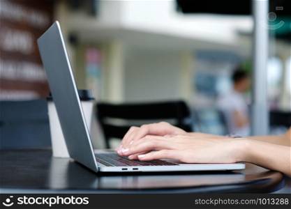 Woman hand using laptop computer at cafe outdoors background, people and technology, lifestyles