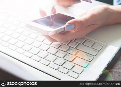 Woman hand using mobile device and laptop on her desk, Online shopping and marketing concept