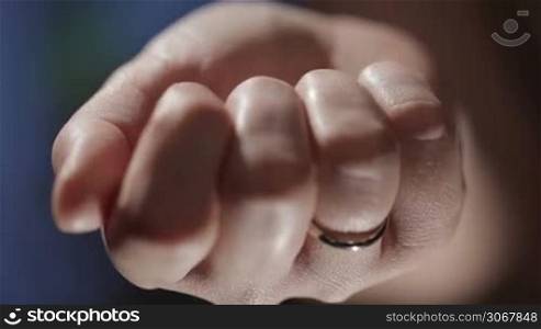Woman hand with a wedding ring holding a key. Close up detail.