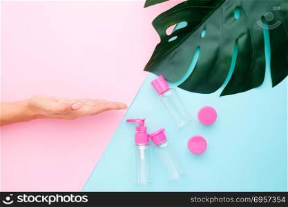 Woman hand with empty bottle for separate lotion or cream on pas. Woman hand with empty bottle for separate lotion or cream on pastel color background, Flat lay of beauty product mock up