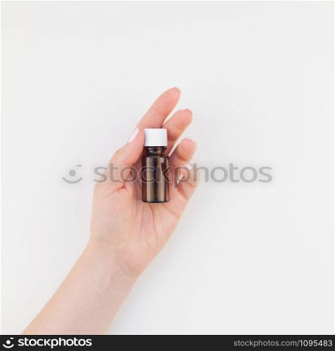 Woman hand with manicure polish holding small glass bottle isolated white background with copy space. Square Mock up for natural oil spa treatment, medical products. Female healthcare wellness concept