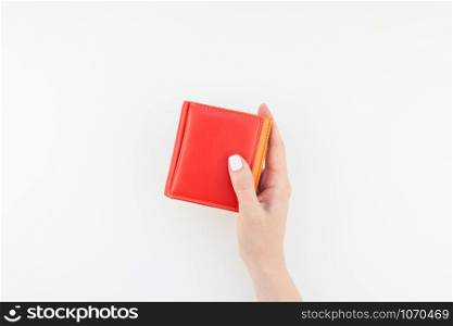 Woman hand with pastel manicure polish holding bright red leather wallet isolated on white background with copy space in minimalism style. Template for feminine beauty blog social financial media