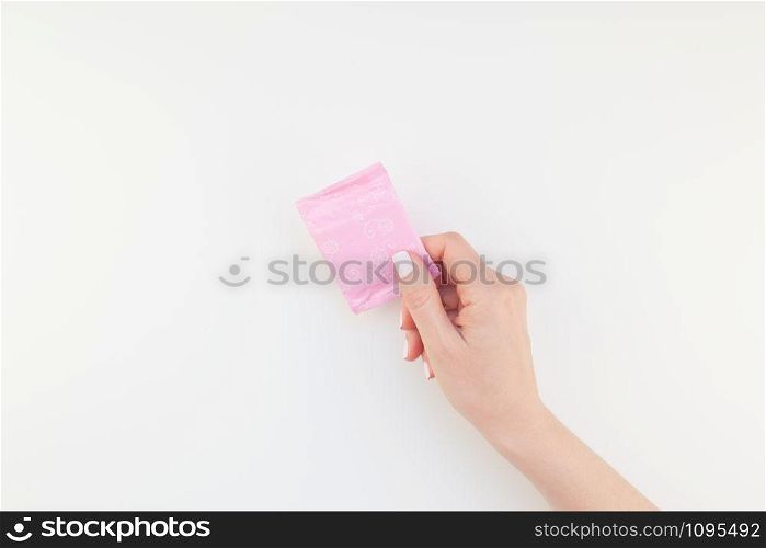 Woman hand with pastel manicure polish holding pink daily sanitary napkin isolated on white background with copy space. Template for feminine beauty blog social media. Female healthcare concept