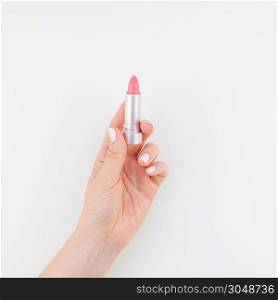 Woman hand with pastel manicure polish holding pink lipstick isolated on white background with copy space. Square template for feminine beauty blog social media