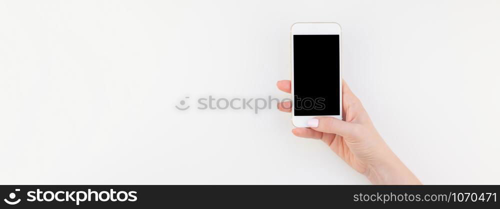 Woman hand with pastel manicure polish holding smartphone isolated on white background with copy space in minimalism style. Long wide banner mock up for feminine blog social technological media