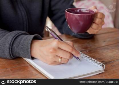 Woman hand with pen writing on notebook, stock photo