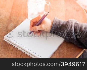 Woman hand with pen writing on notebook, stock photo