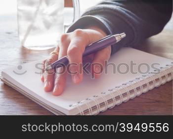 Woman hand with pen writing on notebook with vintage style