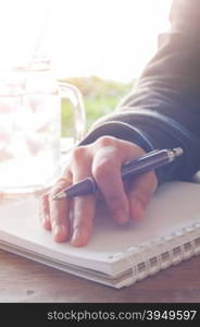 Woman hand with pen writing on notebook with vintage style