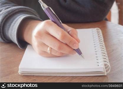 Woman hand with pen writing on notebook with vintage style
