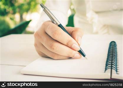 Woman hand with pen writing on white notebook. with copy space.