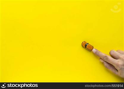 Woman hand with Yellow toy car on a yellow background. Free space for text. Woman hand with Little Yellow toy car on a yellow background. Free space for text