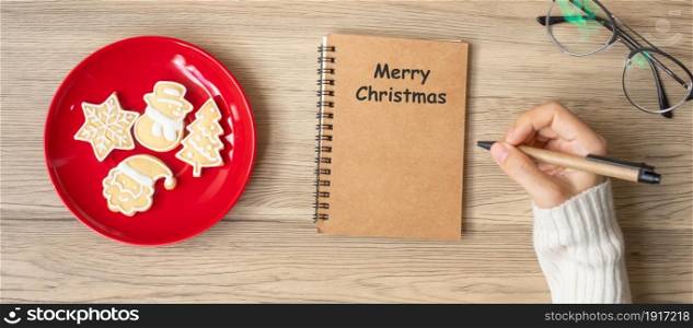 Woman hand writing on notebook with Christmas cookies on table. Xmas, Happy New Year, Goals, Resolution, To do list, Strategy and Plan concept
