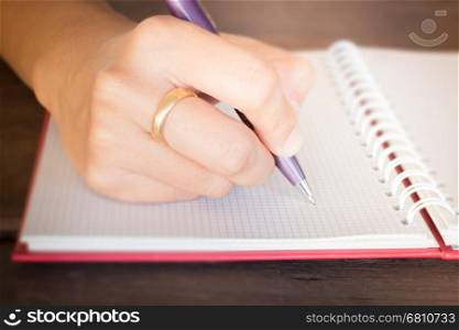 Woman hand writing on noteboook paper, stock photo