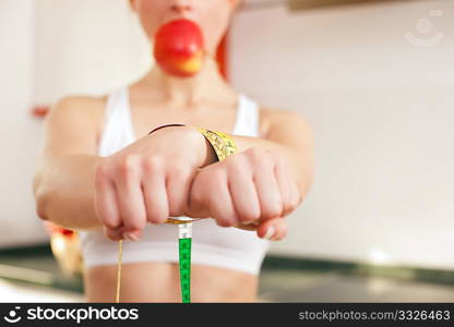 Woman handcuffed by a tape measure and gagged by an apple - symbol for eating disorder