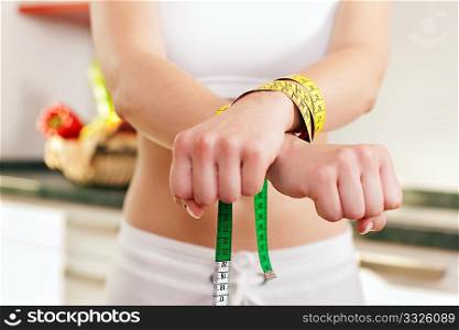 Woman handcuffed by a tape measure - symbol for eating disorder
