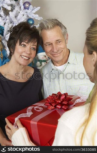 Woman handing senior couple present